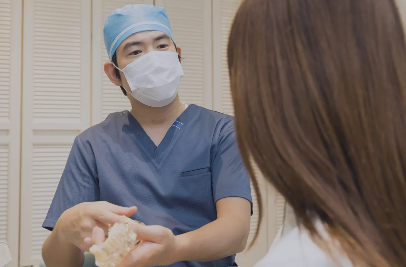 歯の模型を手にして患者さんに説明している医師